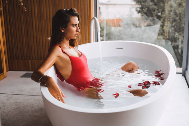 Vrouw zwemmen en ontspannen in een moderne badkuip - Foto, afbeelding
