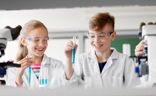education, science and children concept - kids with test tubes studying chemistry at school laboratory - Фото, зображення