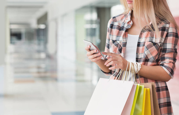 Nő textil smartphone közben shopping mall - Fotó, kép