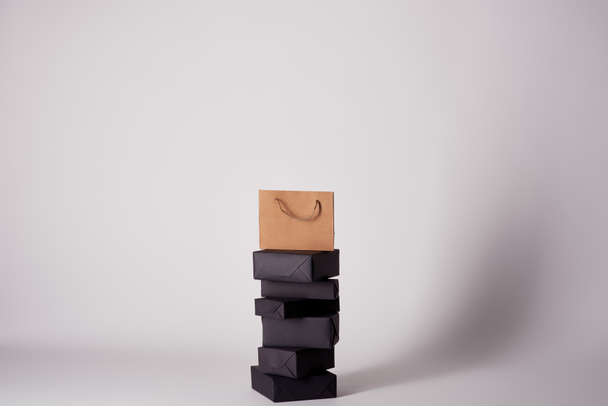 shopping bag on stacked boxes on white surface, black friday concept - Foto, Imagem