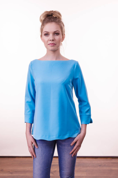 Dorosła kobieta prezentuje swój nieformalny piękny strój, niebieską bluzkę z długim rękawem i dżinsy. - Zdjęcie, obraz
