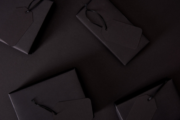 Ansicht von Black Boxes mit Tags auf schwarzer Oberfläche, Black-Friday-Konzept - Foto, Bild