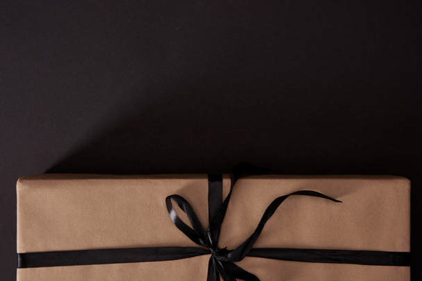 top view of craft wrapped gift box on black surface, black friday concept - Photo, Image