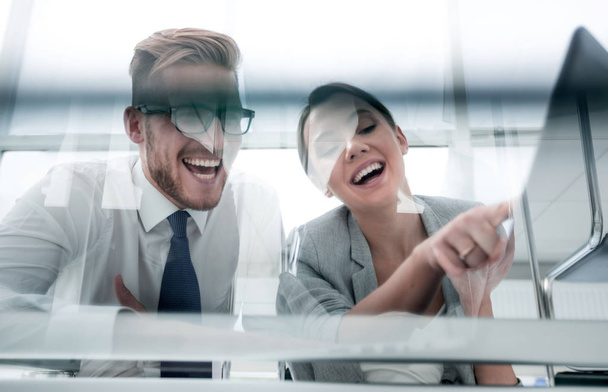 from the glass.smiling business couple sitting at the Desk - Photo, Image