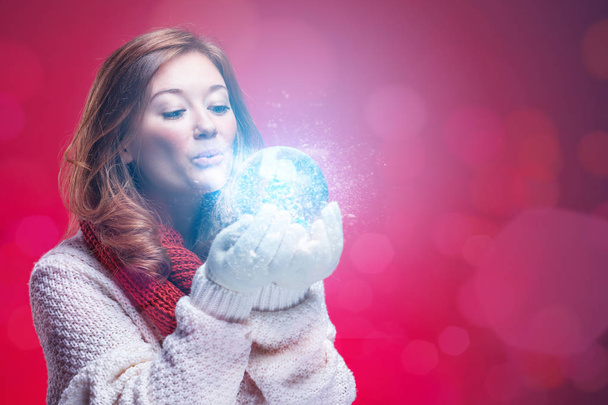 Side close up portrait of a joyful young woman holding a snow globe - Foto, afbeelding