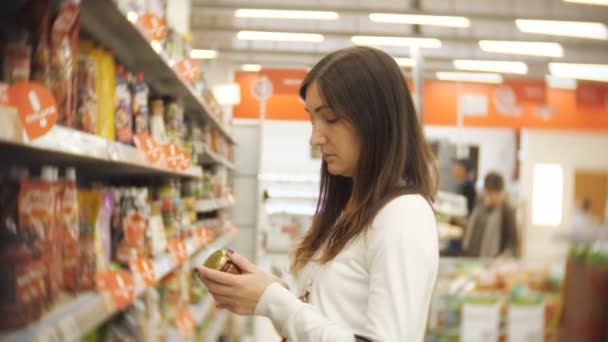 junge Frau steht in einer Ketchupflasche in den Händen eines Supermarktes - Filmmaterial, Video