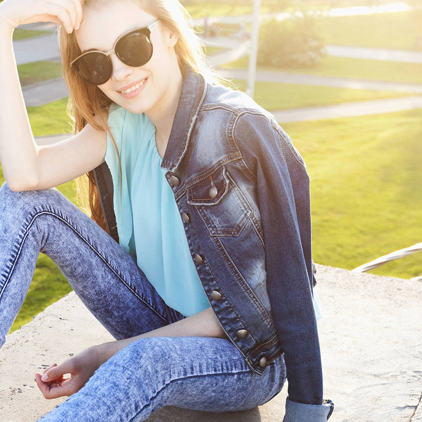 Beautiful young girl with sunglasses smiling on sunny street. Lifestyle Concept - Zdjęcie, obraz