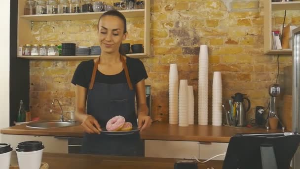Smiling waitress giving cup of coffee and donats to the customer. - Video