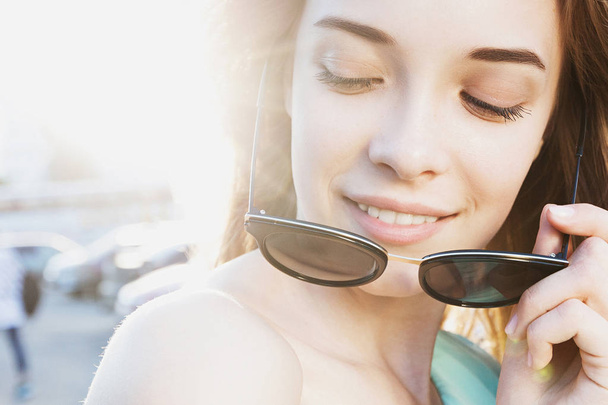 Beautiful young girl with sunglasses smiling on sunny street. Lifestyle Concept - Valokuva, kuva