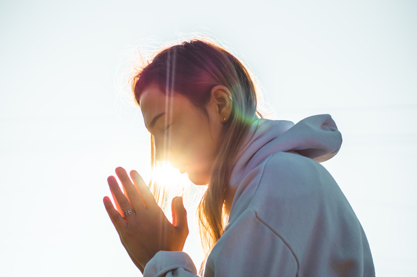In de ochtend die meisje haar ogen sloot, bidden buiten, gevouwen handen in gebed concept voor geloof, spiritualiteit, religie concept. - Foto, afbeelding
