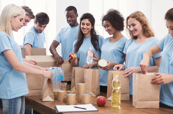 Freiwillige packen Essen und Getränke in Papiertüten - Foto, Bild