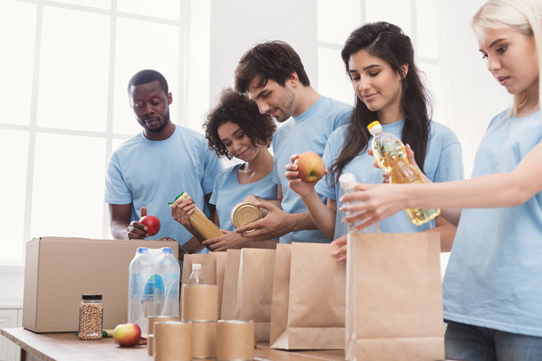 Voluntarios empacando alimentos y bebidas en bolsas de papel
 - Foto, imagen