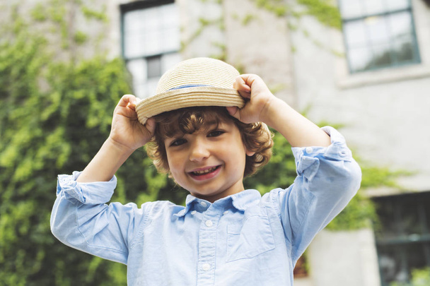 Portrait of Cute little boy standing in city street with his hat - Fotoğraf, Görsel