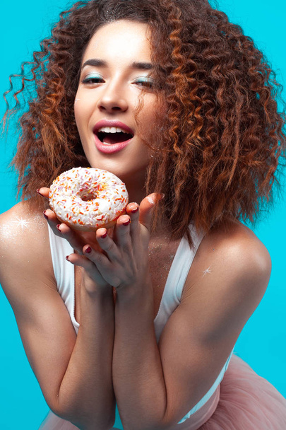 Beautiful young cheerful girl with donut in hand. Fun, food and holiday concept - Фото, изображение