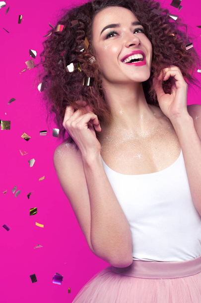 Beautiful smiling young woman on pink background with flying confetti. Holiday concept - Φωτογραφία, εικόνα