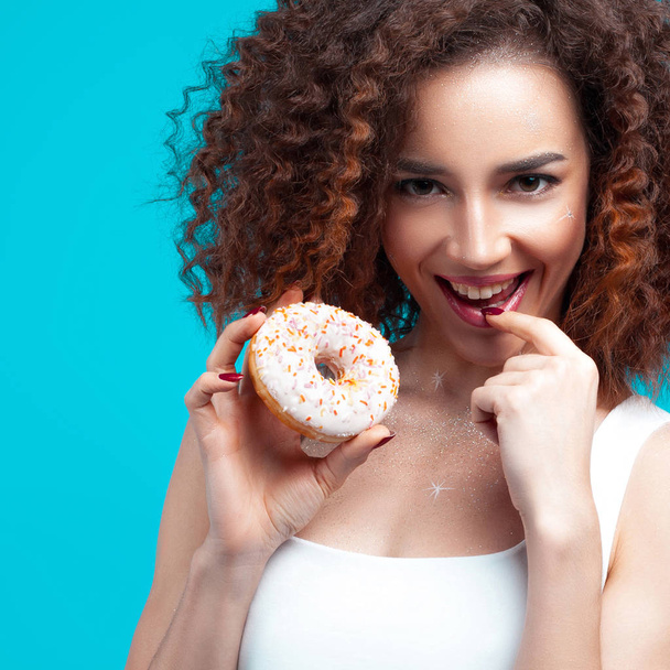 Beautiful young cheerful girl with donut in hand. Fun, food and holiday concept - Φωτογραφία, εικόνα