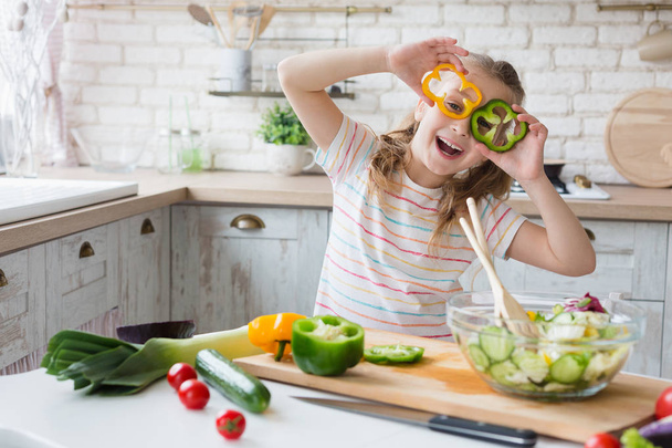 Μικρό κορίτσι Διασκεδάζοντας με φέτες πιπέρι στην κουζίνα - Φωτογραφία, εικόνα