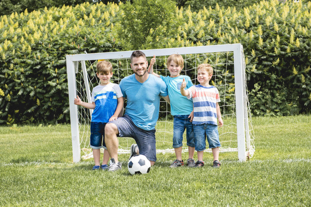 野球場の外でサッカーをしている子供を持つ男 - 写真・画像