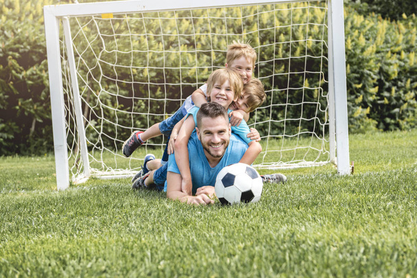 Muž s dítětem hraje fotbal venku na hřišti - Fotografie, Obrázek