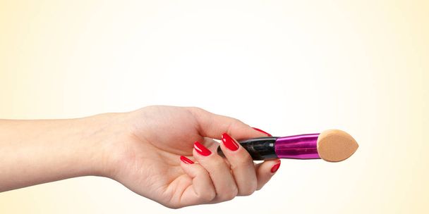 Woman hand with a foundation cosmetic tool isolated on color background - Φωτογραφία, εικόνα