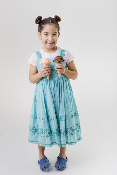 Little girl holding two ice cream cones - 写真・画像