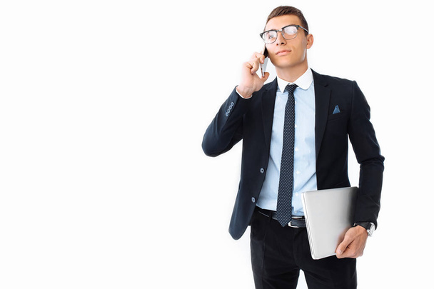 Business man, in a suit and glasses, talking on the phone and holding a laptop in his hand, on a white background - Foto, immagini