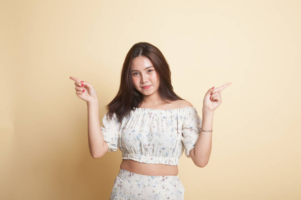 Young Asian woman point to left and right on beige background - Foto, Imagen