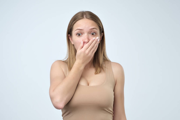 Surprised young woman with long eyelashes covering with hands her mouth - Photo, Image
