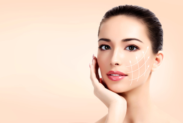 Detailní záběr ženské hezkou tvář s bílými šipkami na kůži pro kosmetické lékařské procedury, pastelové pozadí. Koncept péče o pleť - Fotografie, Obrázek
