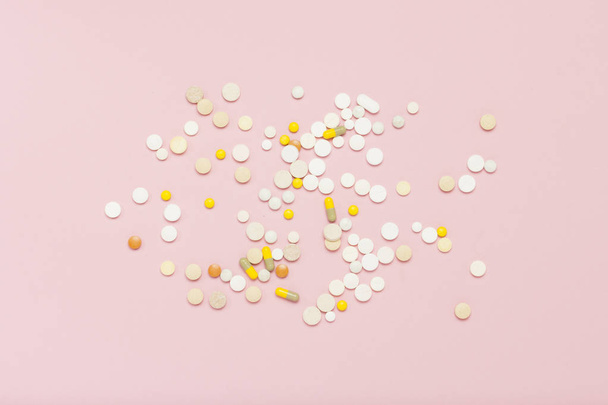 Pills of different sizes and colors on a light pink background. Concept of the pharmaceutical industry, daily vitamins and minerals for women. Pregnancy, menopause. Flat lay, top view. - Photo, Image