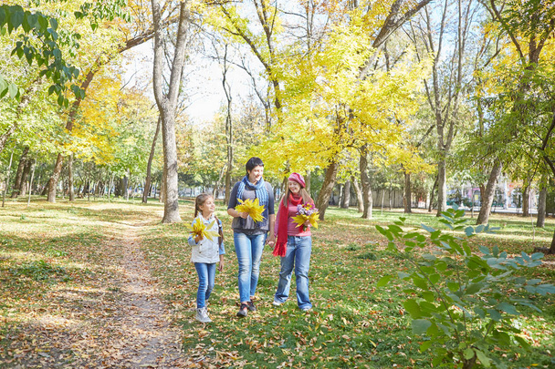 Happy family. Loving mother and two daughter in autumn park. One daughter with a disability with Down syndrome. Positive human emotions, feelings. - Фото, изображение