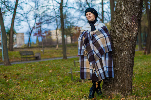 Atractiva mujer de mediana edad cubierta con un paseo manta en otoño
  - Foto, Imagen