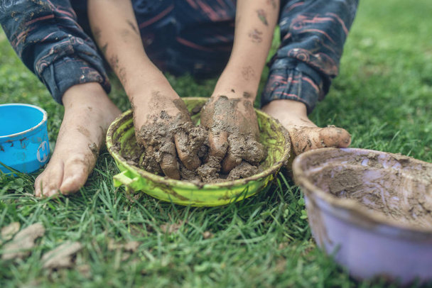 Retro obrázek batole dítě sedící v trávě hrál s bahnem s špinavé ruce a nohy. - Fotografie, Obrázek