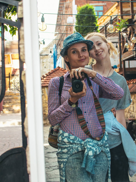 Twee toeristen nemen een selfie met de hulp van een spiegel en een camera. - Foto, afbeelding