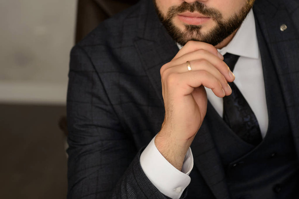 De knappe, blanke man in een grijs pak met een stropdas, clouse uitzicht op zijn hand - Foto, afbeelding