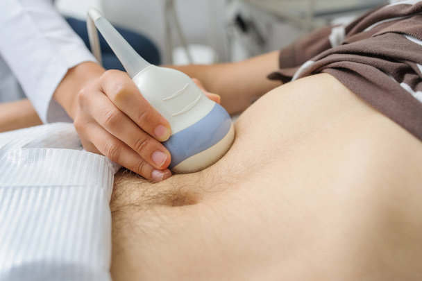 Nainen lääkäri tutkii miehen vatsan ultraäänitutkimuslaitteella - Valokuva, kuva
