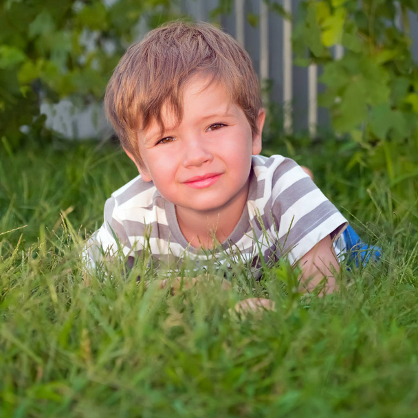 Lindo chico teniendo actividades al aire libre. Niño en la hierba
. - Foto, imagen