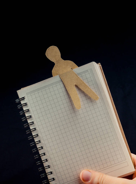 Ανδρικό σχήμα κομμένο από χαρτί σε notebbok στο χέρι - Φωτογραφία, εικόνα