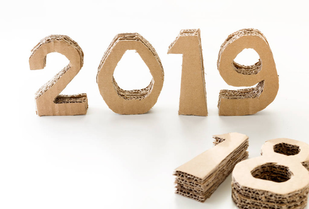 2019 met 18 neer handgemaakte 3d nummers gemaakt van hergebruikt karton papier, op witte achtergrond. Nieuwjaar concept. - Foto, afbeelding