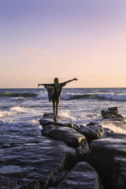 hermosa rubia sobre rocas por el océano
 - Foto, imagen