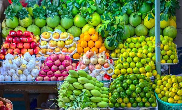 Tiendas de frutas en el mercado con todo tipo de mandarinas. granada, naranja, manzana, pera, uva, mango, fruta del dragón, lichi... todo arreglado en estantes se ven atractivos y llamativos
. - Foto, imagen