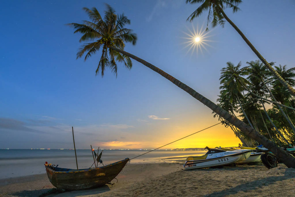 Luar brilhante na bela praia com coqueiros inclinados e o barco do pescador na aldeia de pescadores do Vietnã
 - Foto, Imagem