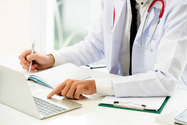 Médecin travaillant sur un ordinateur portable à la table du bureau de l'hôpital. Concept médical et de santé
. - Photo, image
