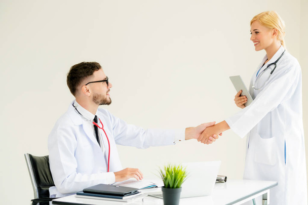 Doctor at the hospital giving handshake to another doctor showing success and teamwork of professional healthcare staff. - Φωτογραφία, εικόνα
