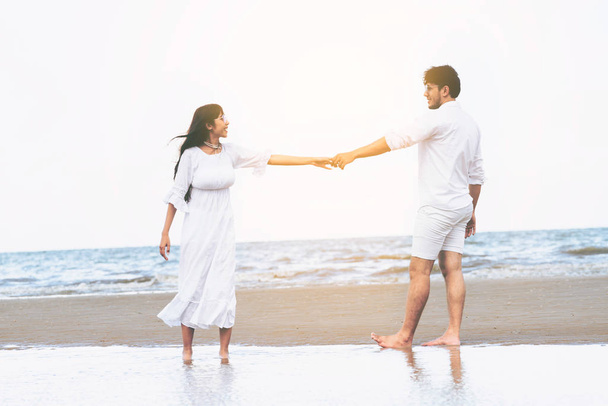 Ευτυχισμένο ζευγάρι πηγαίνει γαμήλια ταξίδια σε τροπική παραλία με άμμο το καλοκαίρι. - Φωτογραφία, εικόνα