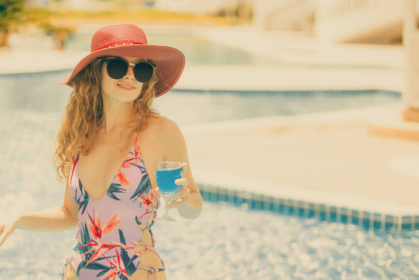 Happy young woman wearing swimsuit having good time at swimming pool in luxury resort. Summer travel holiday concept. - Zdjęcie, obraz