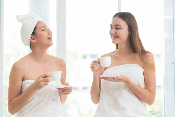 Two women drinking tea or herbal drinks while having conversation in luxury day spa. Wellness, leisure and healthcare concept. - Foto, Imagem