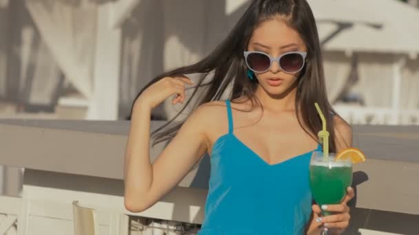 Nuori aasialainen muoti nainen juo cocktail rannalla baarissa
. - Materiaali, video