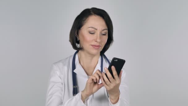 Lady Doctor Browsing Smartphone, White Background - Filmati, video