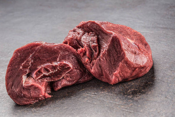 Portion of raw beef meat on dark butcher board. - Fotoğraf, Görsel